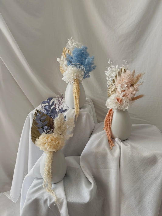 Three decorative vases with dried flowers on a white fabric background. Small dried flower arrangements that are custom made. Customise and create your own little flower piece. 